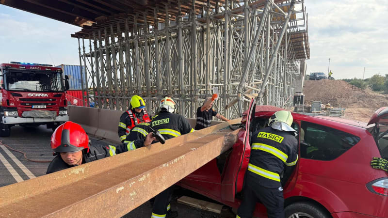 Na auto na Kladensku spadla mostní traverza. Hasiči vyprostili dvě osoby, zasahoval vrtulník